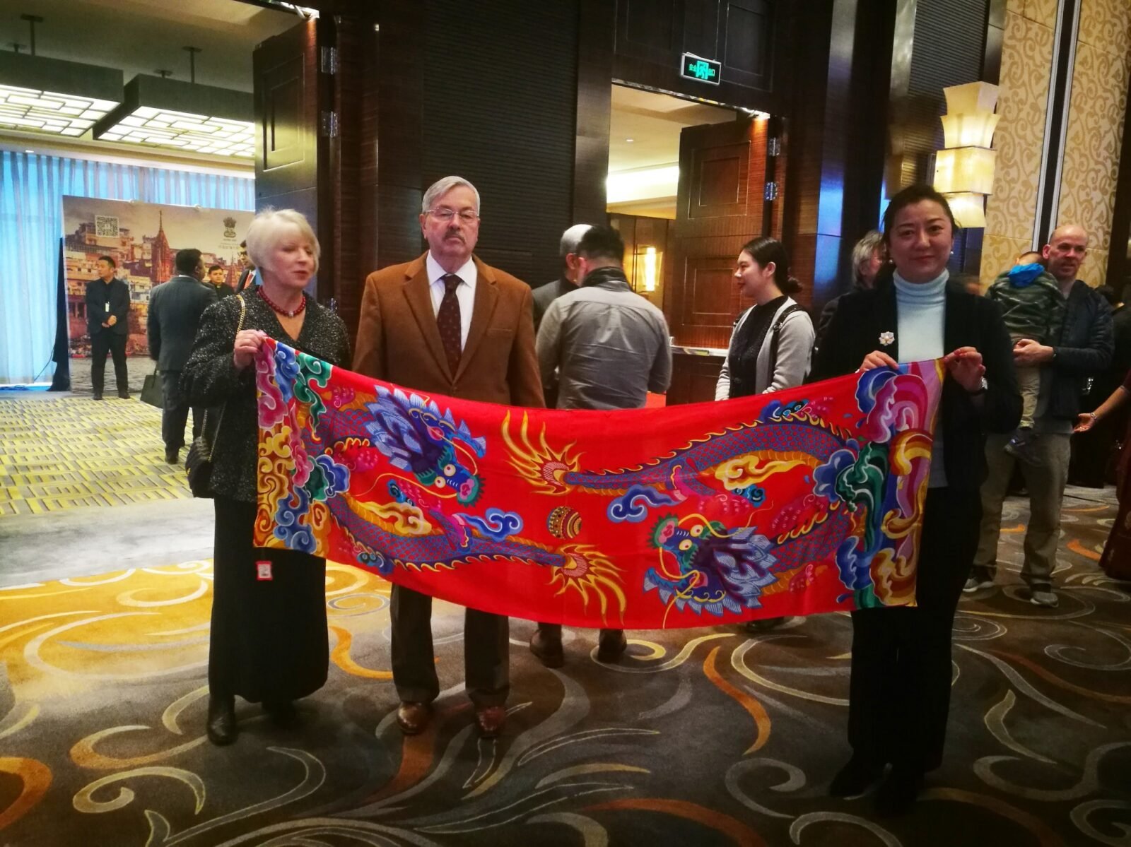 On January 28, 2019, the current US Ambassador to China, Terry Branstad (pictured), praised the "Double Dragon Play Bead" long scarf produced by Aurora Group's brand "Silkworm Seal" with Chinese style.